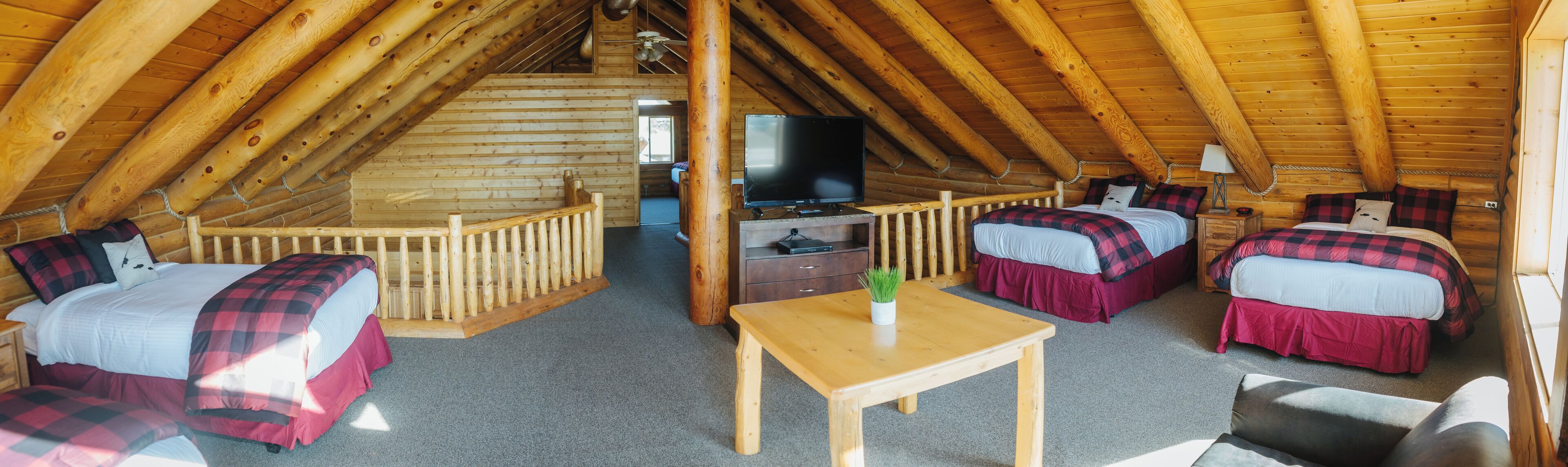 A cozy cabin with a loft bedroom, a TV, and a small table.