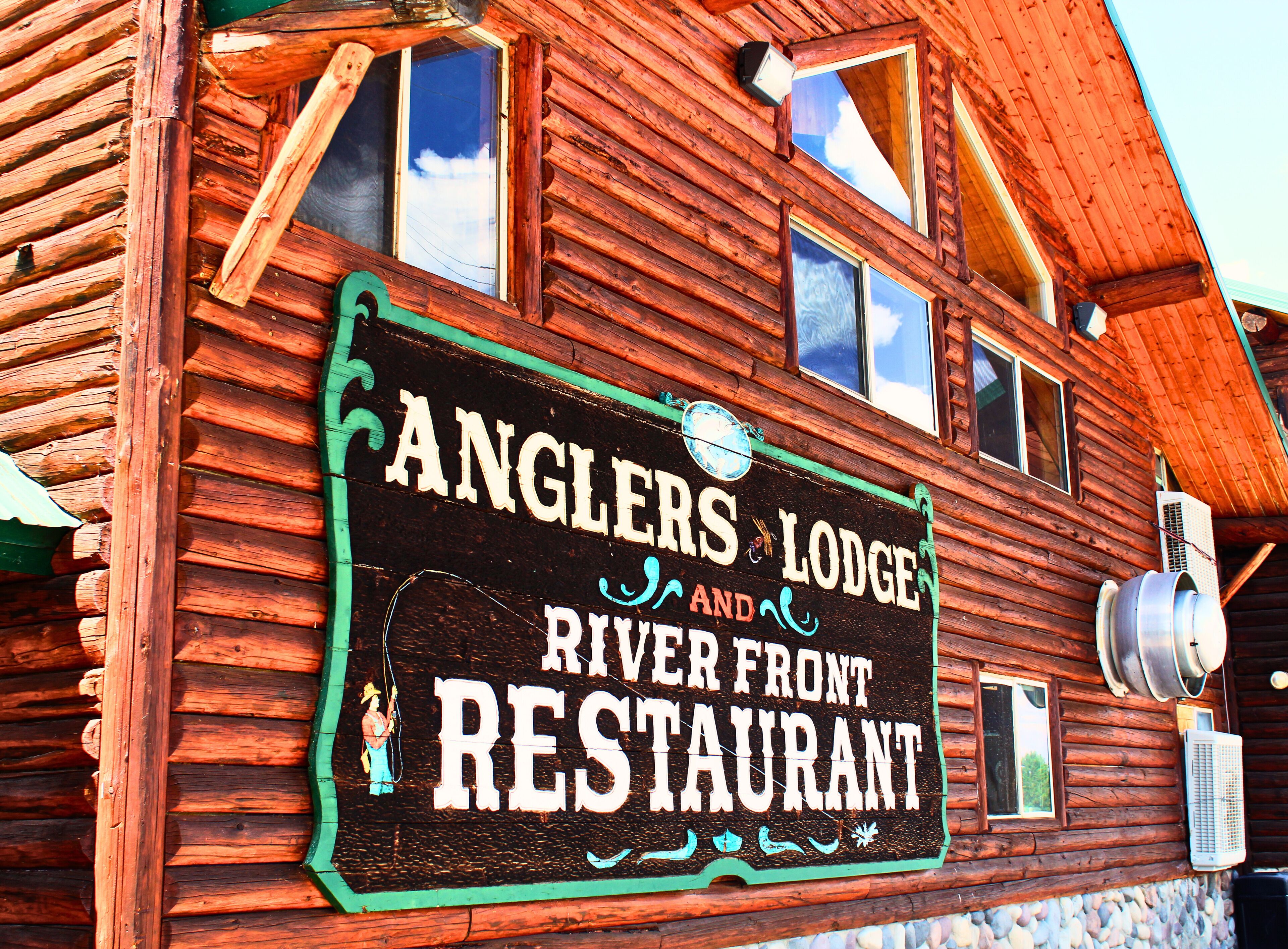 A wooden building with a sign that reads "Anglers Lodge and River Front Restaurant".