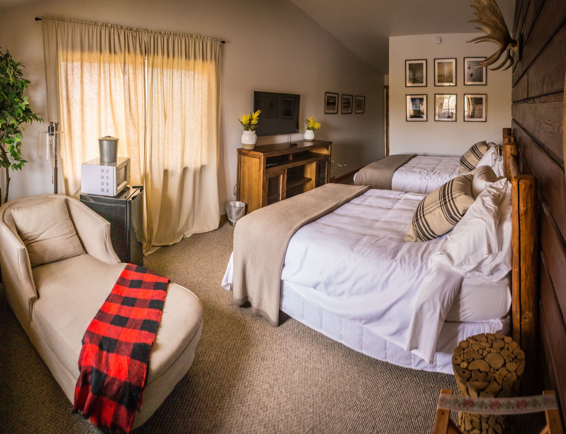 Una habitación de hotel acogedora con cama, una silla, un escritorio con televisor y una chimenea.
