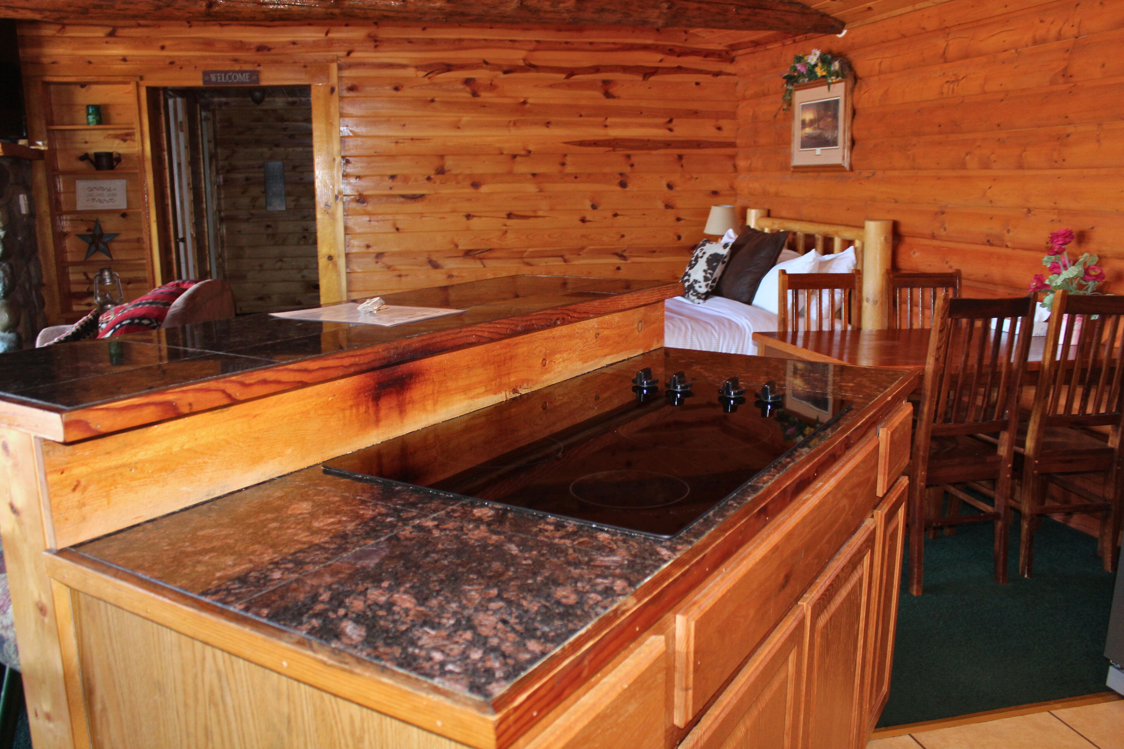 L’intérieur d’une cabane en bois comprend un espace cuisine doté de plans de travail en granit, d’un évier et de meubles de rangement en bois.