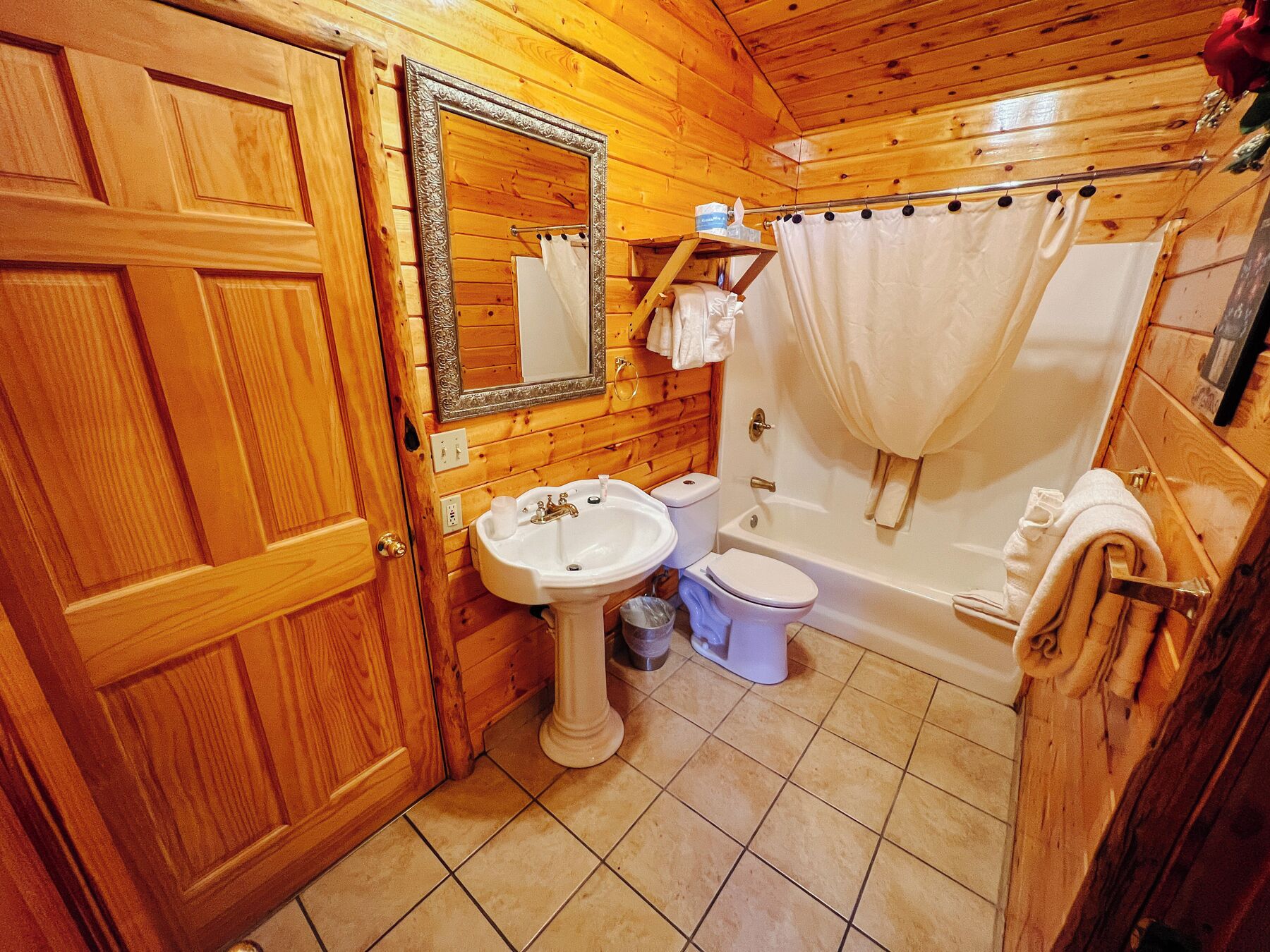 Un baño de cabaña de madera con lavamanos, inodoro y bañera.