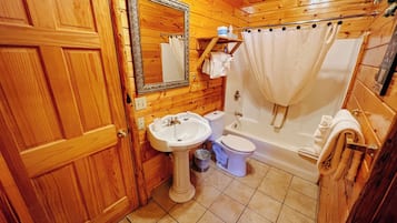A wooden cabin bathroom with a sink, toilet, and bathtub.