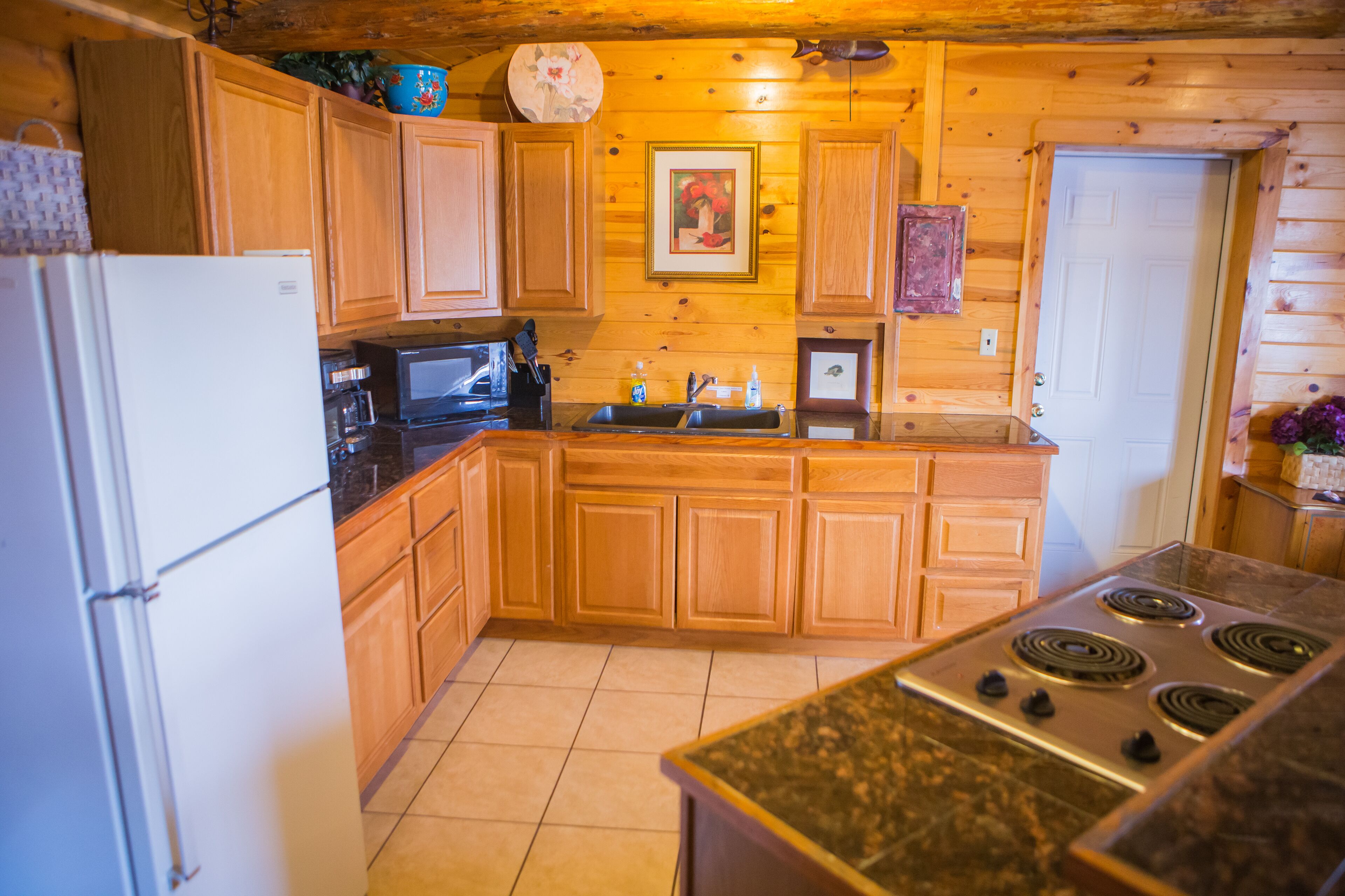 A kitchen with wooden cabinets, a stove, a microwave, and a refrigerator.