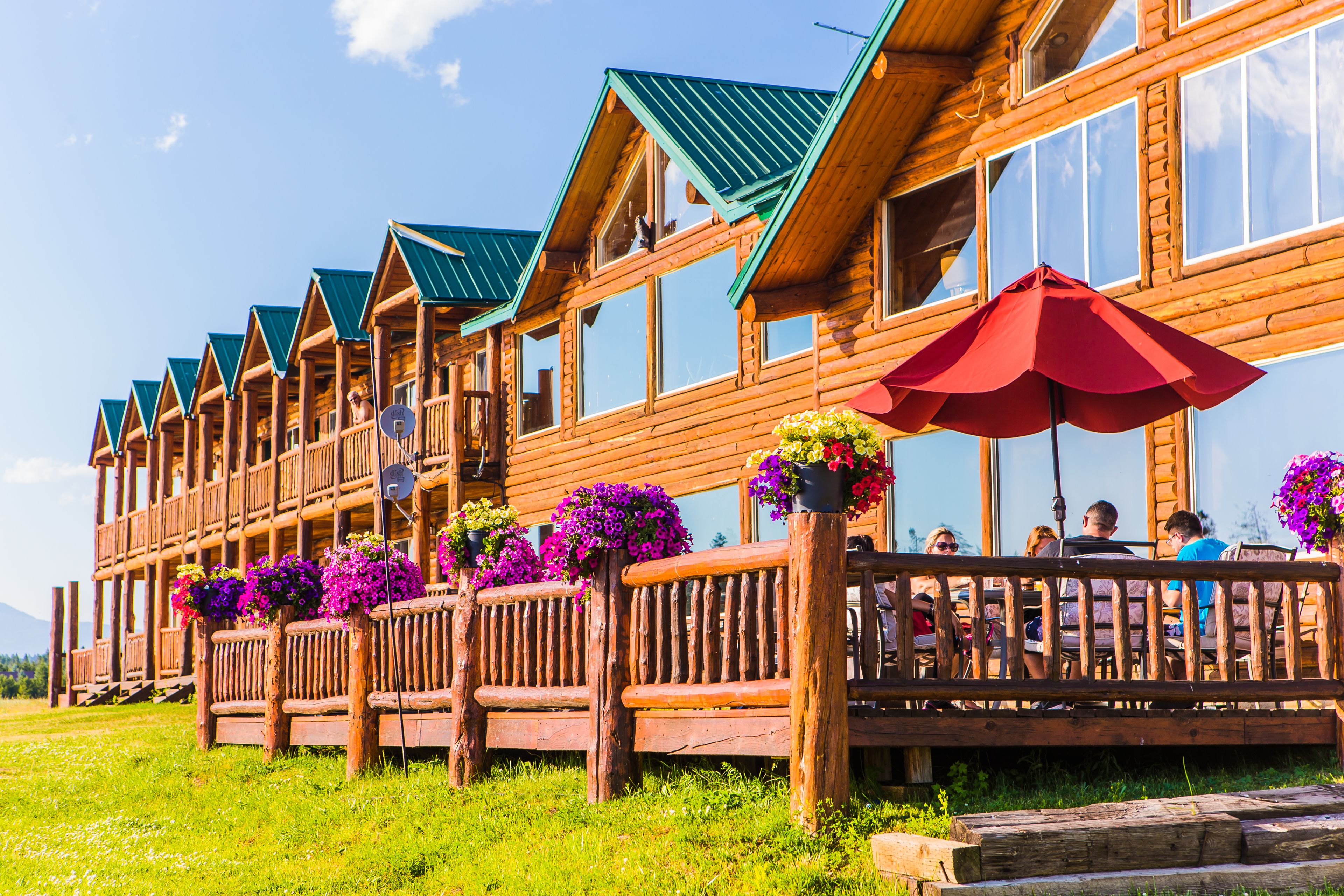 A wooden lodge with multiple balconies, outdoor seating, and flower baskets.