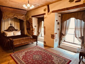 A traditional room with a bed, a red patterned rug, and a wooden ceiling.