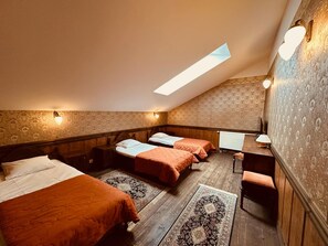 Quarto com três camas, uma escrivaninha e um radiador.