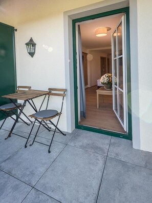 An outdoor patio with a table and chairs, a door leading inside, and a potted plant. - Hotel Gasthof Mostwastl (Salzburg)