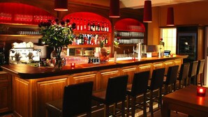 Un espace bar doté d’un long comptoir, de nombreux tabourets et d’une variété de bouteilles et de verres disposés sur des étagères.