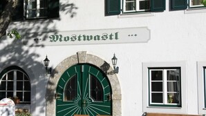 Un bâtiment avec une porte verte et des fenêtres en arc de cercle, portant l’inscription « Mostwastl ».