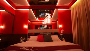 Ein Hotelzimmer mit einem großen Bett, roten Wänden und einer dekorativen Deckenleuchte.