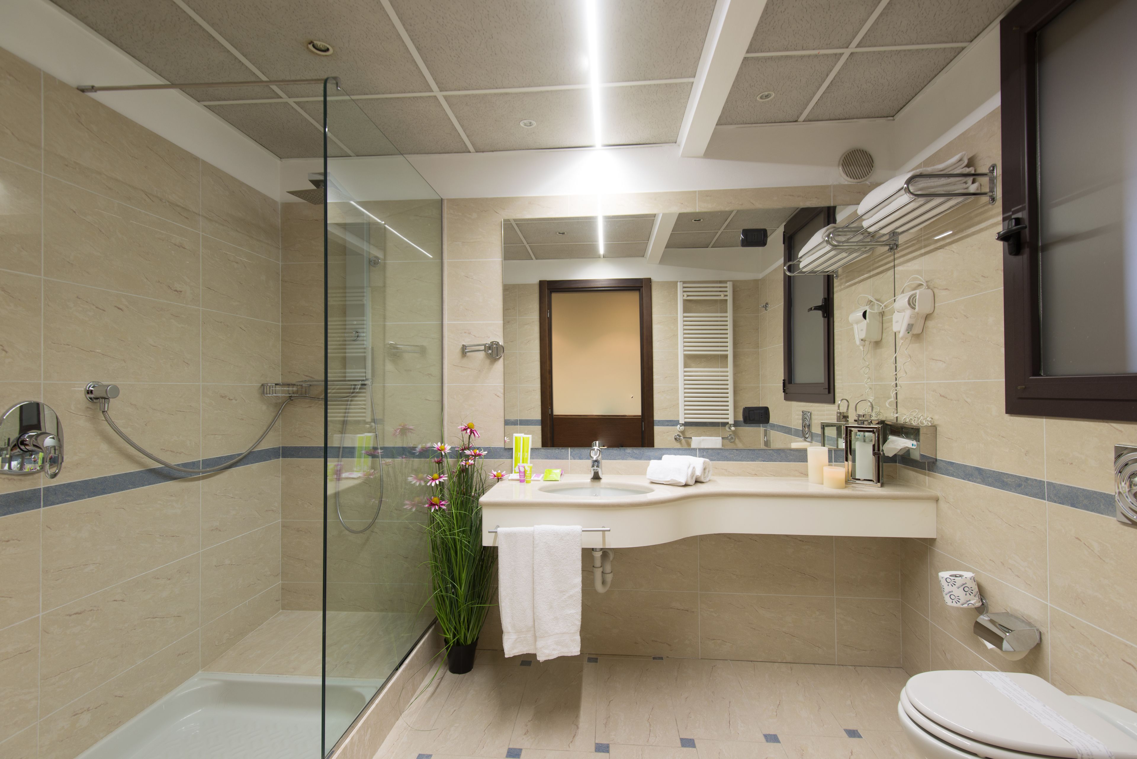 Un baño moderno con cabina de ducha de vidrio, un lavabo con toalla y un inodoro.