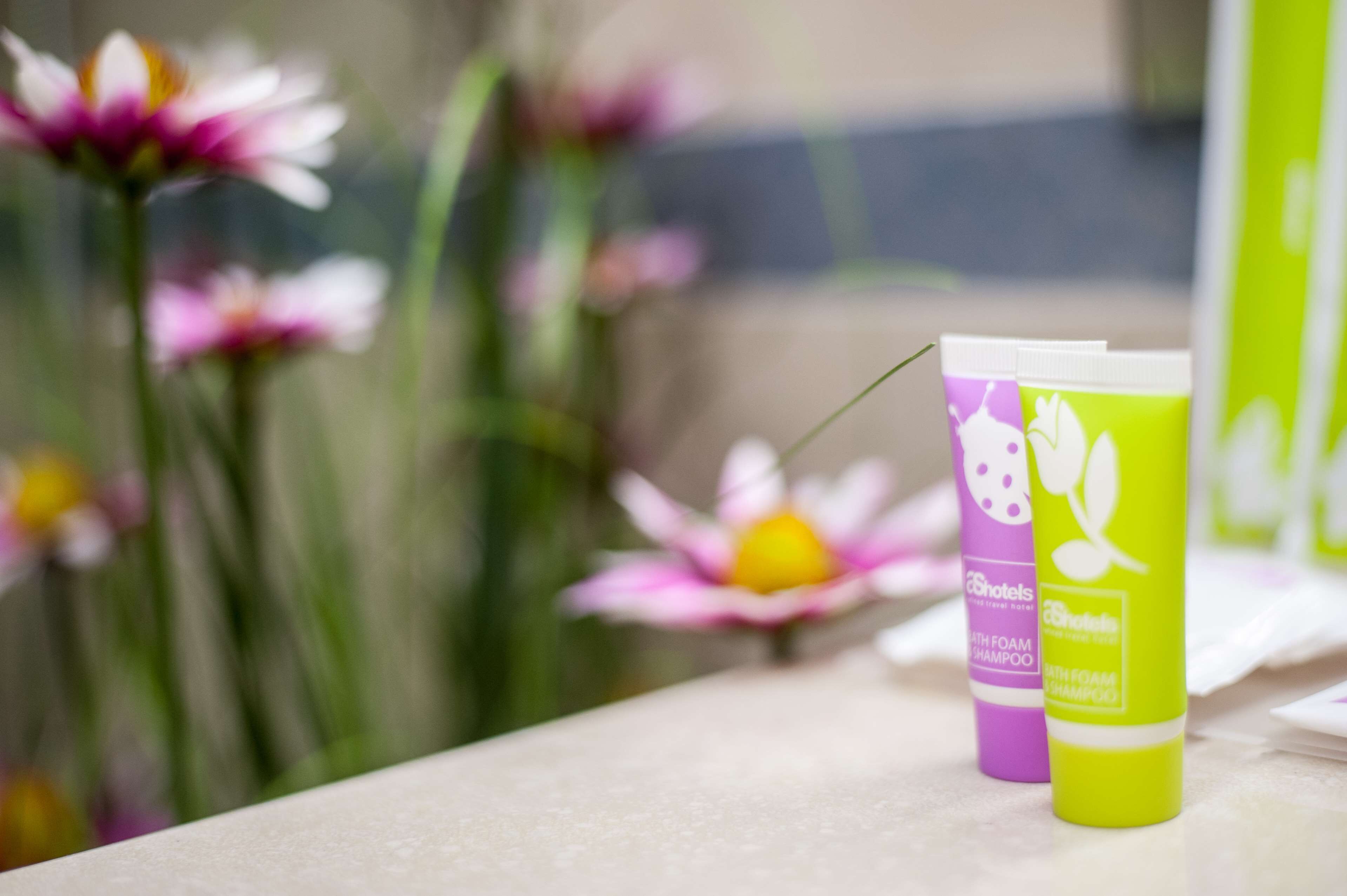 Two shampoo bottles on a counter with a blurred background of flowers.