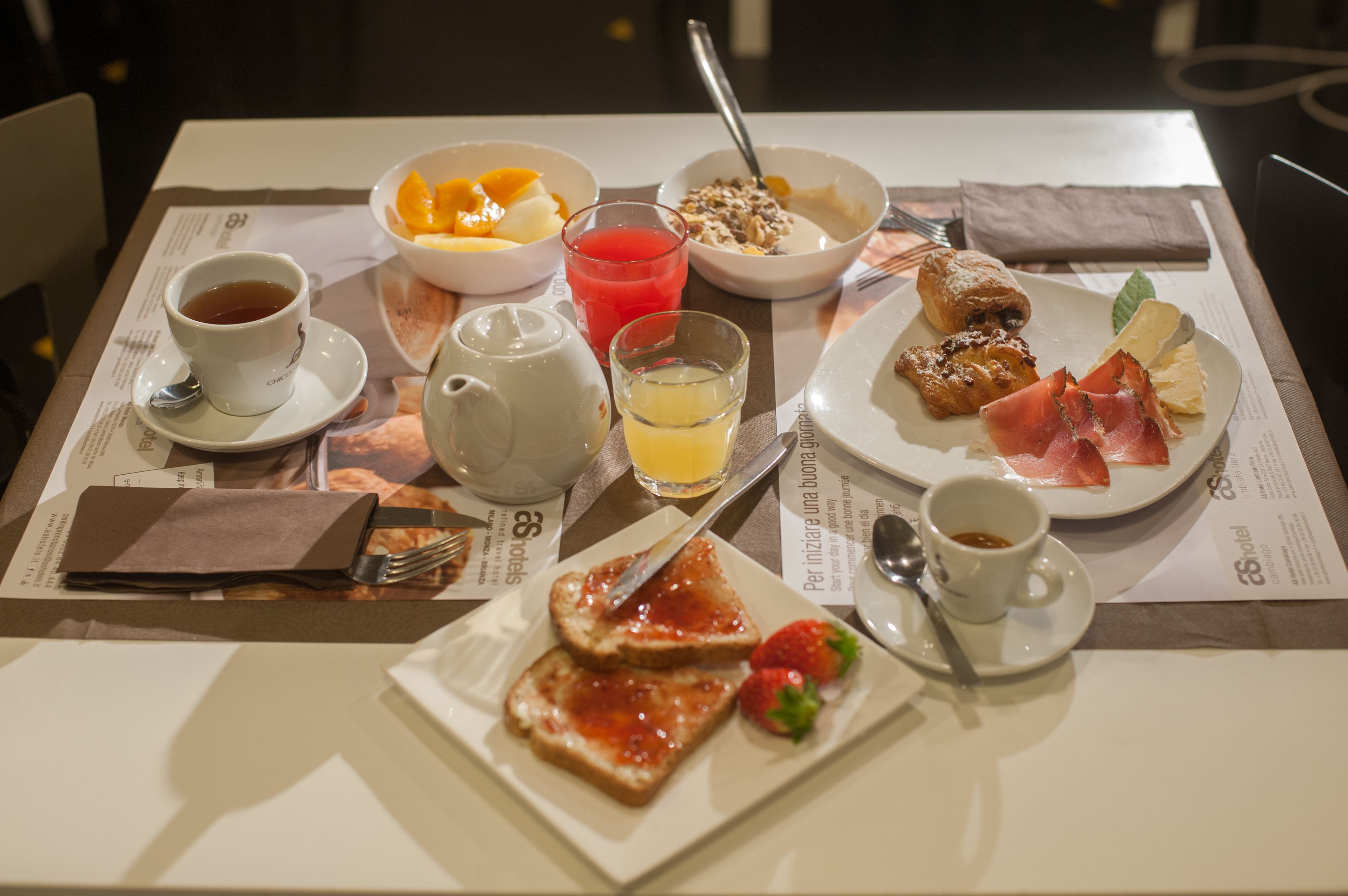A breakfast setting with toast, fruit, cereal, and coffee on a table.