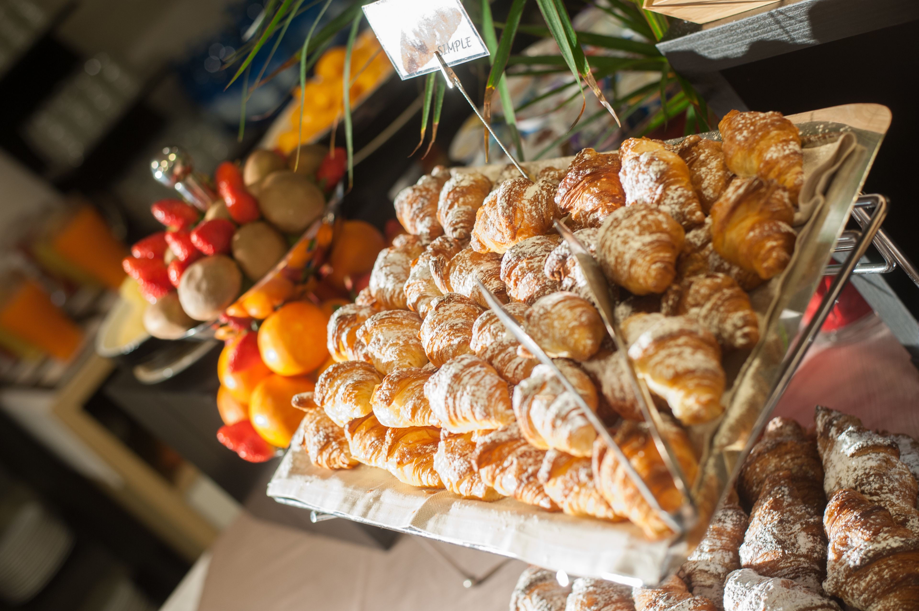 Eine Auswahl an Gebäck und Früchten, darunter Croissants und Orangen.