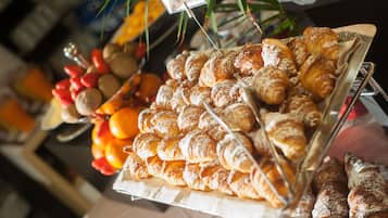 Eine Auswahl an Gebäck und Früchten, darunter Croissants und Orangen.