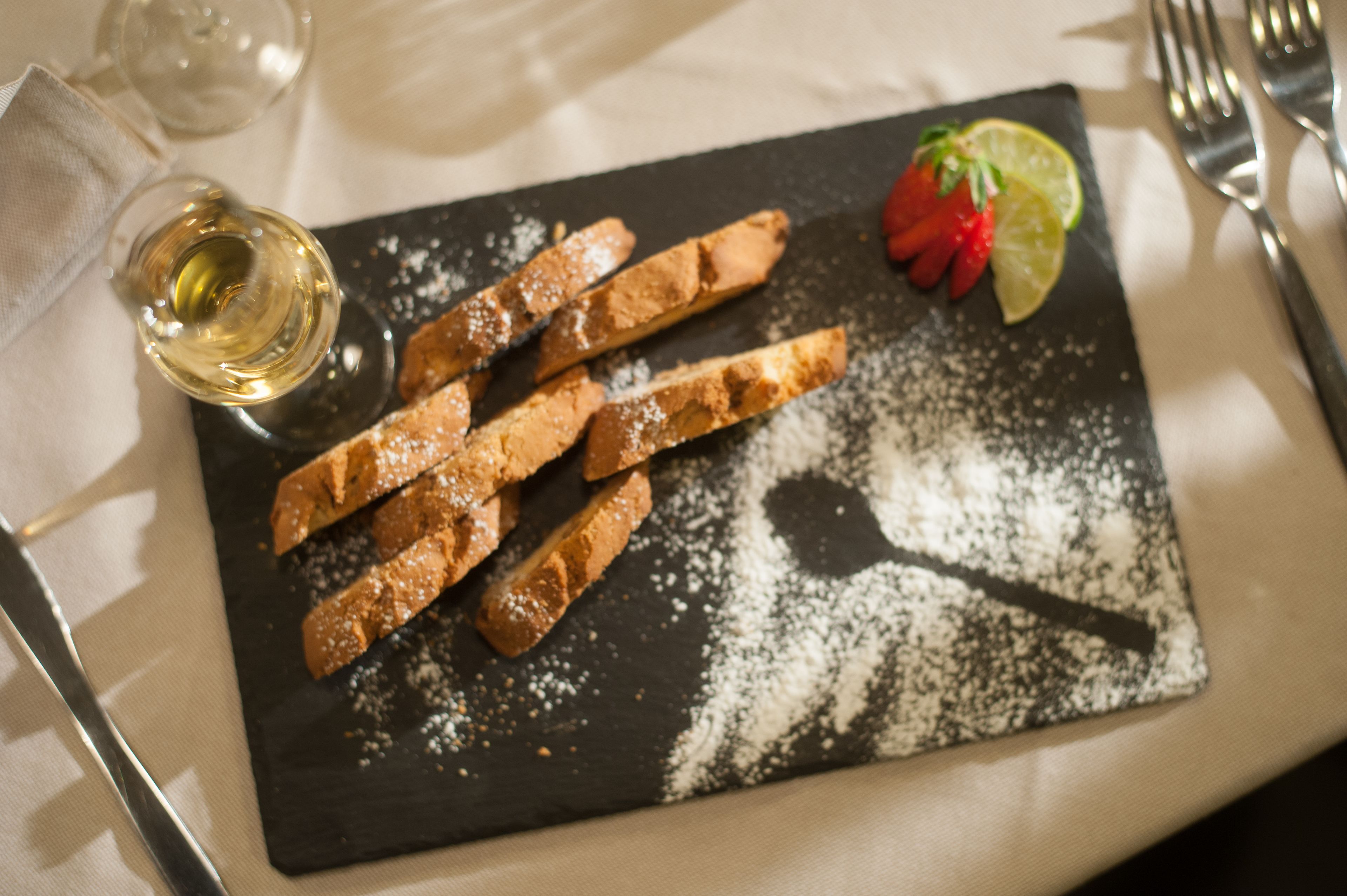 A dessert plate with powdered sugar, a strawberry, and a lime wedge.
