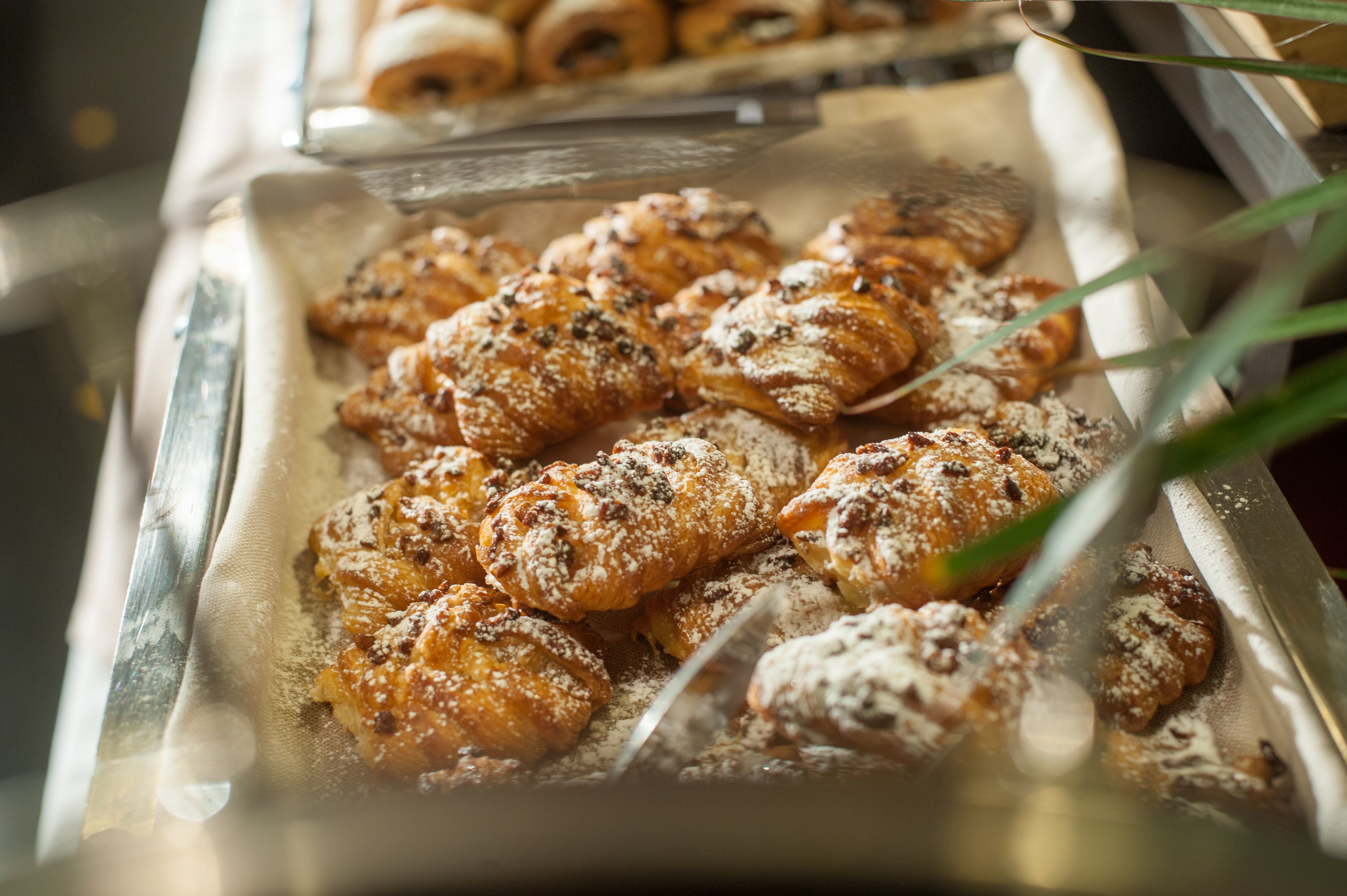 A display of pastries, including croissants and danishes, dusted with powdered sugar.