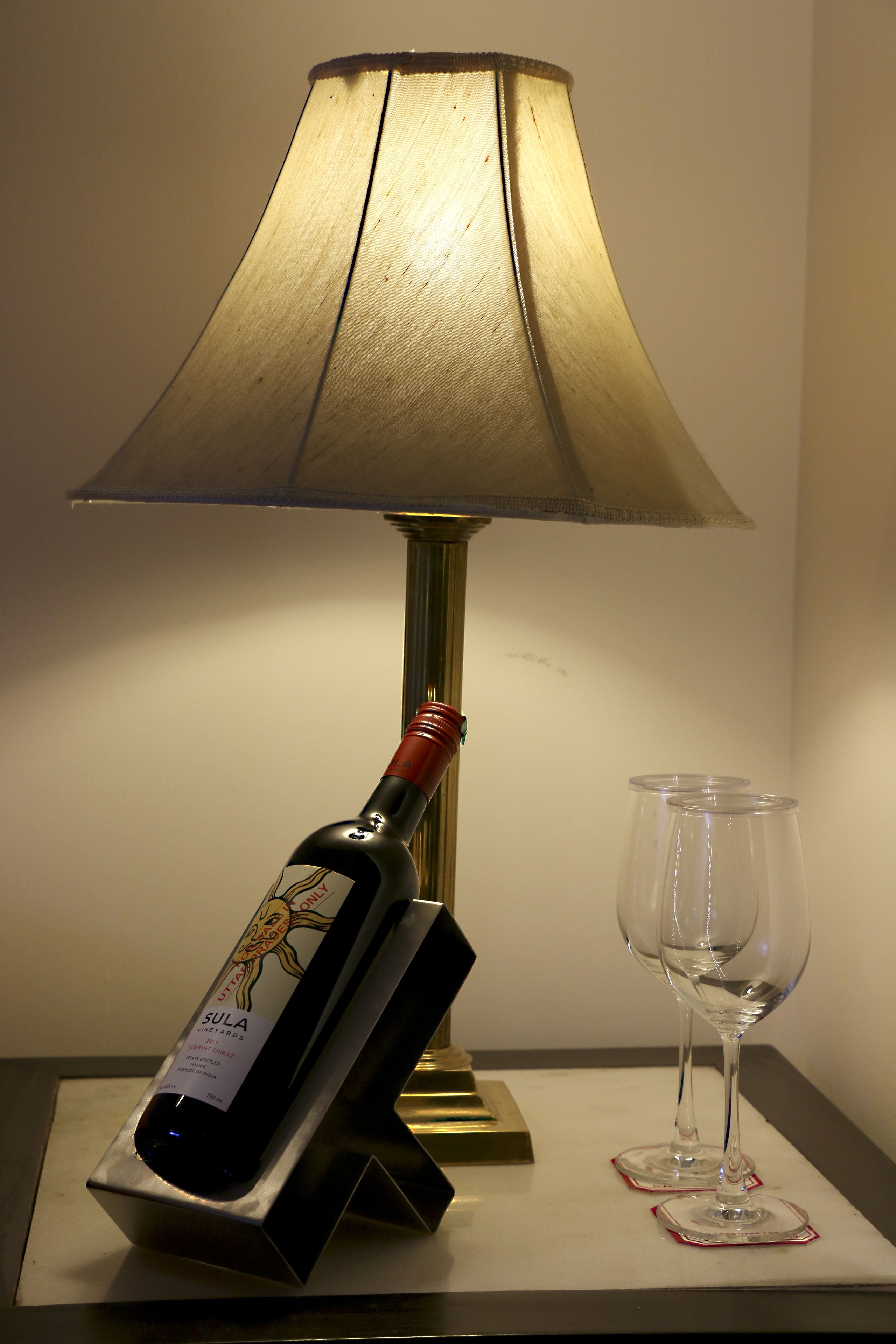 Ett bord med en vinflaska och två glas, placerade på underlägg.