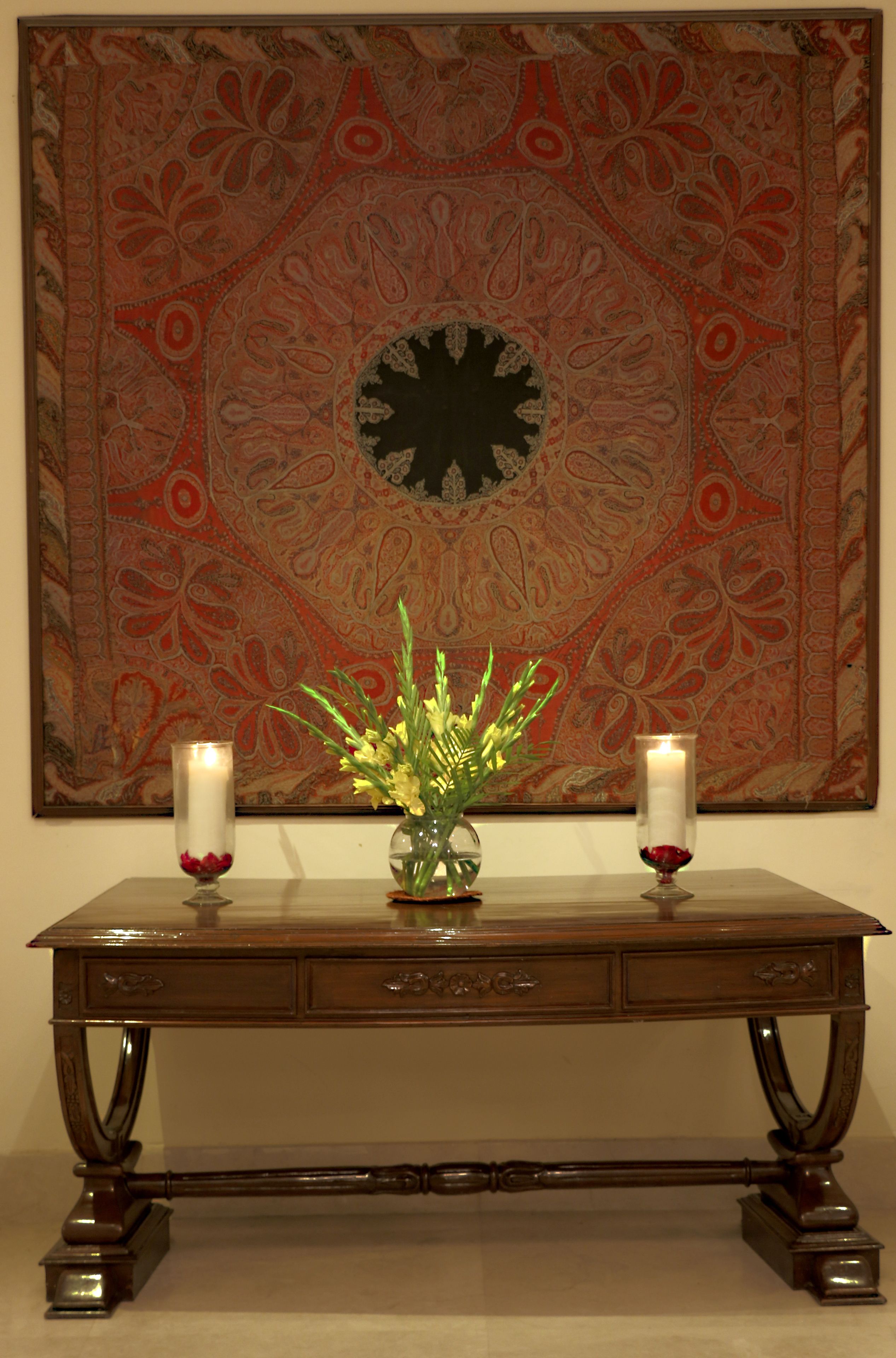 A wooden table with two candles and a vase of flowers.