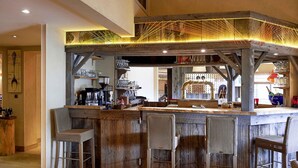 A rustic bar area with wooden bar stools, a coffee machine, and various glassware. - ibis Styles Cholet (Cholet)