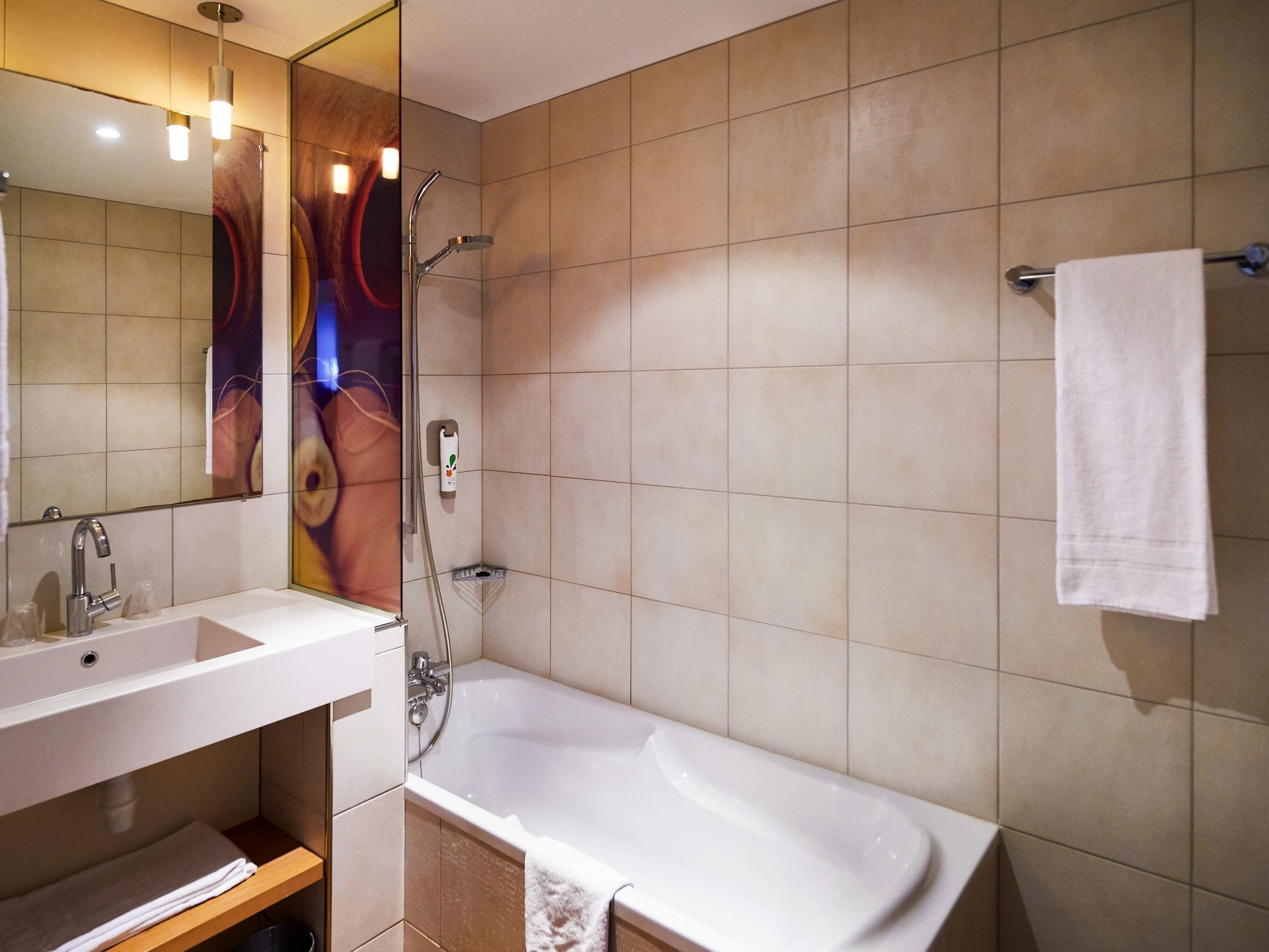 A bathroom with a sink, mirror, shower, and bathtub.