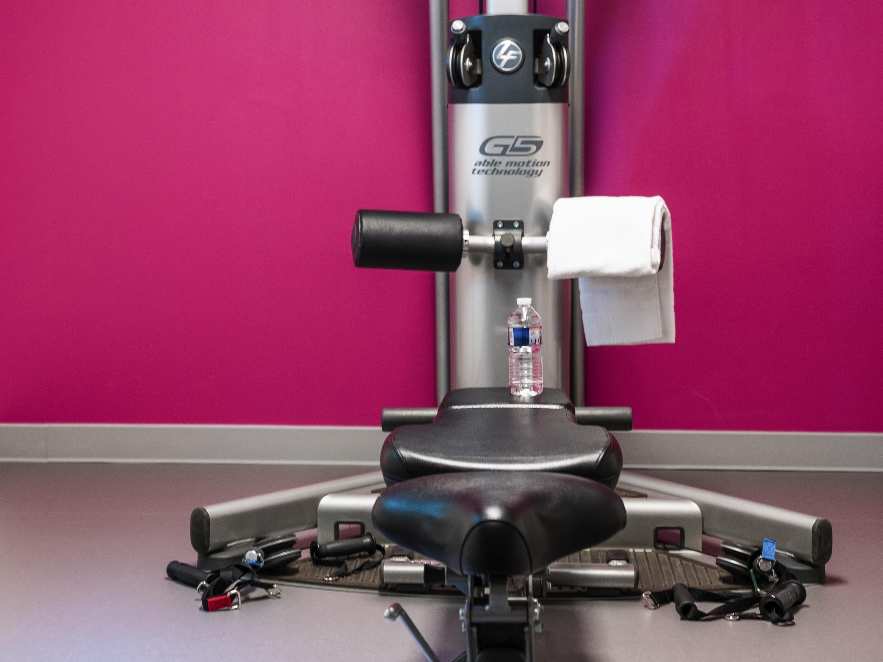 A gym with a stationary bike, a water bottle, and exercise equipment.