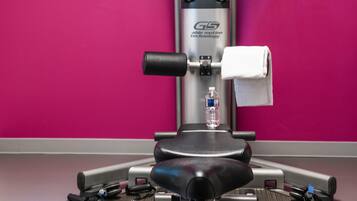 A gym with a stationary bike, a water bottle, and exercise equipment.