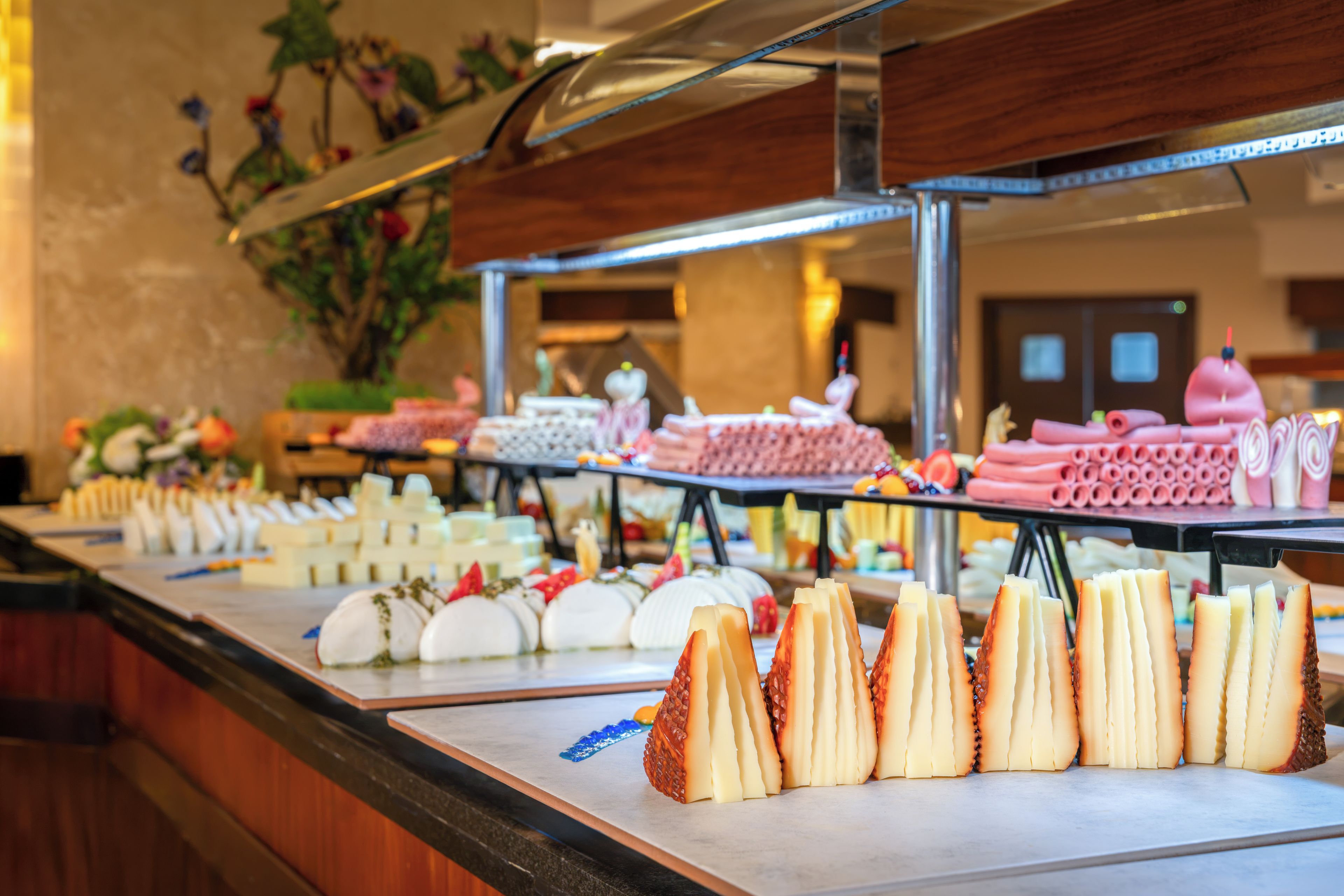 A buffet with various food items including cheeses, fruits, and pastries.