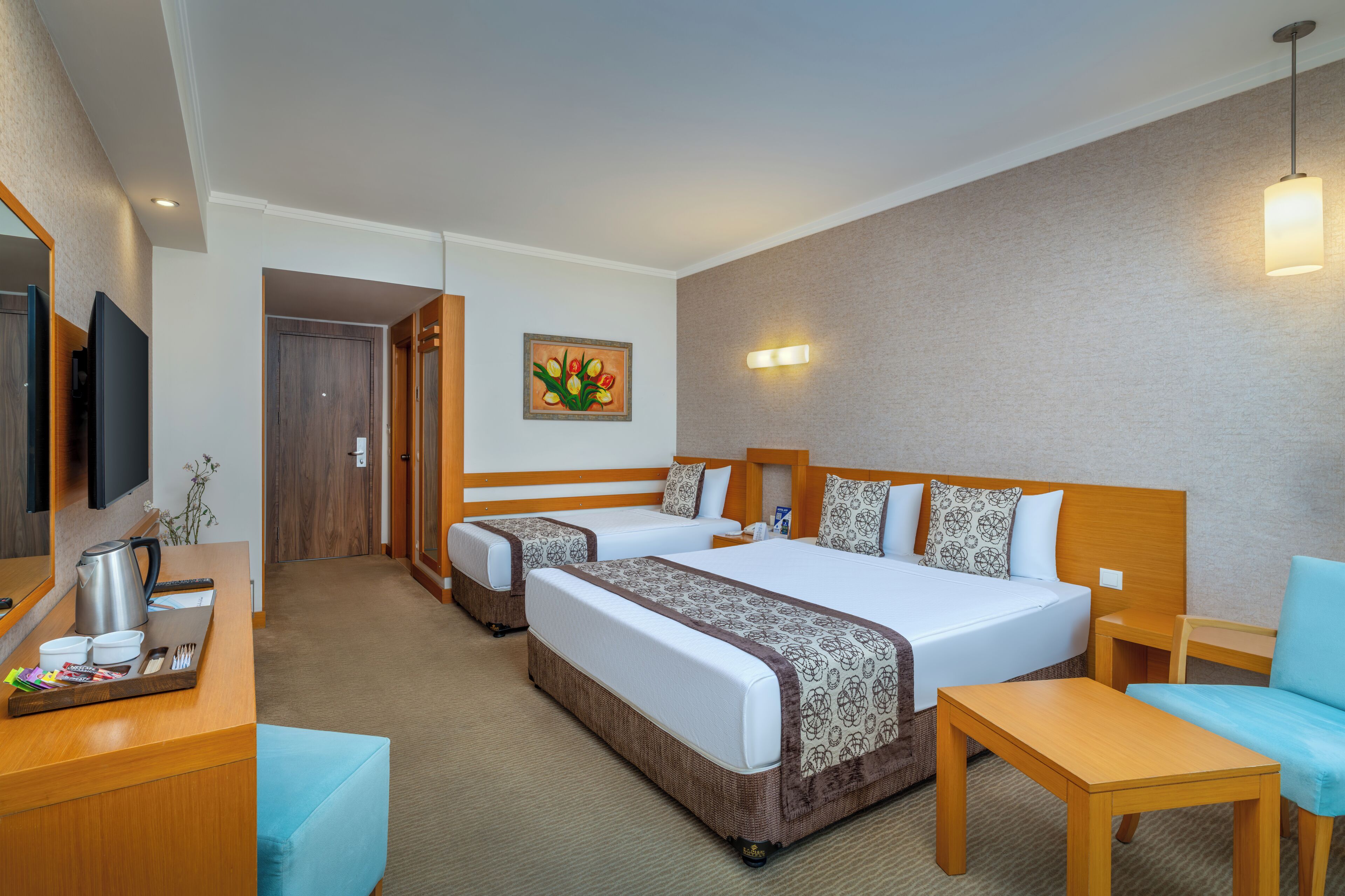 A hotel room with two beds, a desk, a chair, a coffee maker, and a painting on the wall.