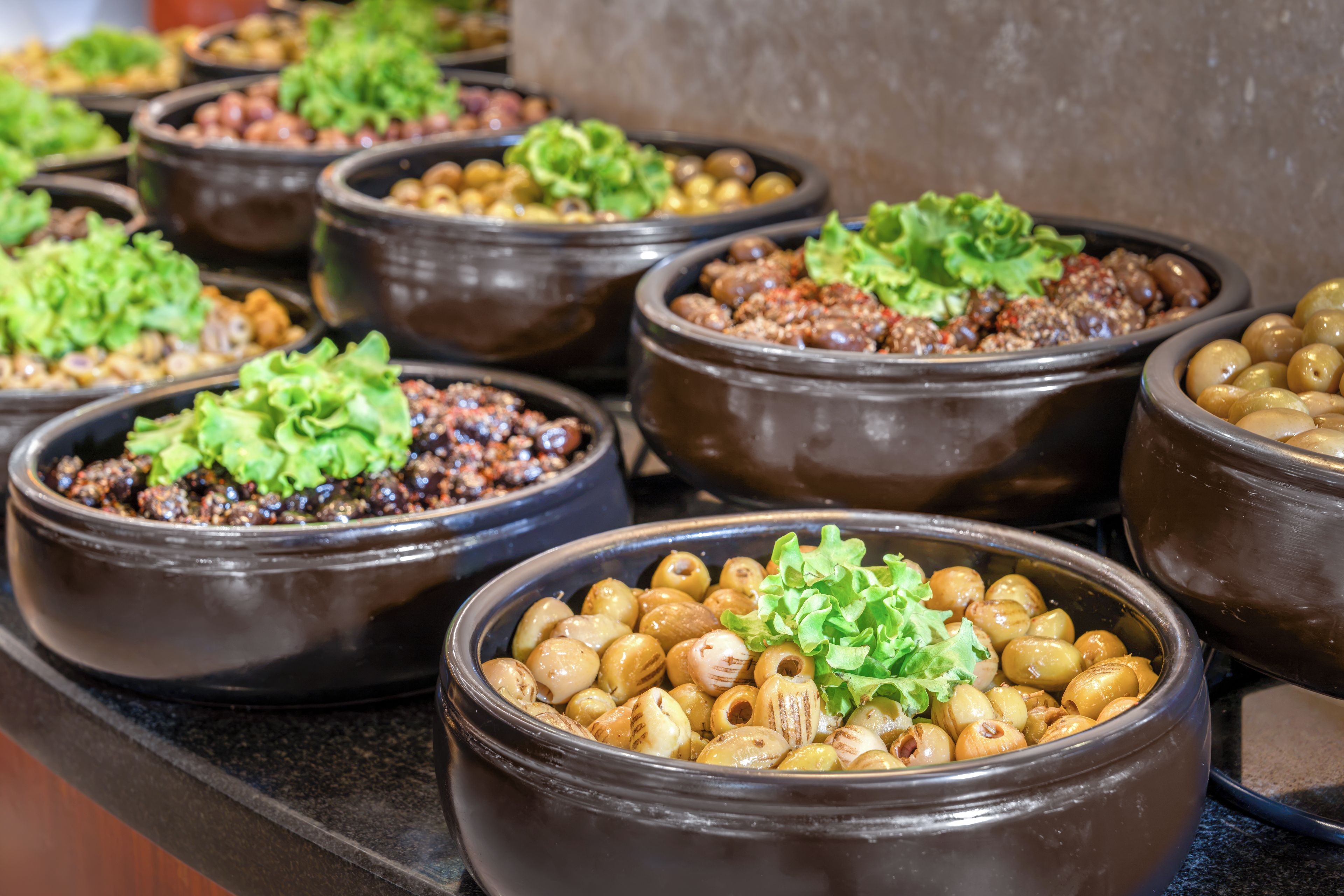 A variety of dishes served in ceramic bowls, some topped with green lettuce.