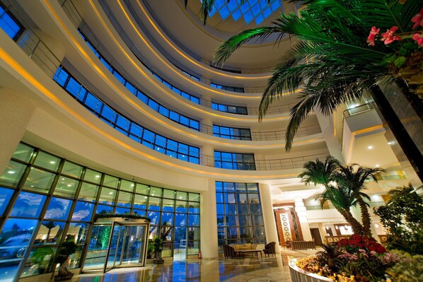 A multi-level atrium with glass railings, palm trees, and a reception area. - Saphir Resort & Spa (Alanya)