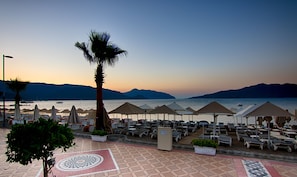 A beachside resort with sun loungers, umbrellas, and a palm tree. - Romance Beach Hotel (Marmaris)