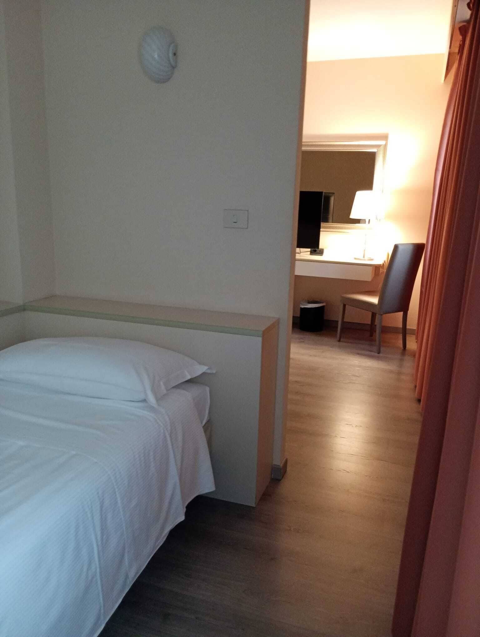 Una habitación de hotel con cama, escritorio, silla y lámpara.