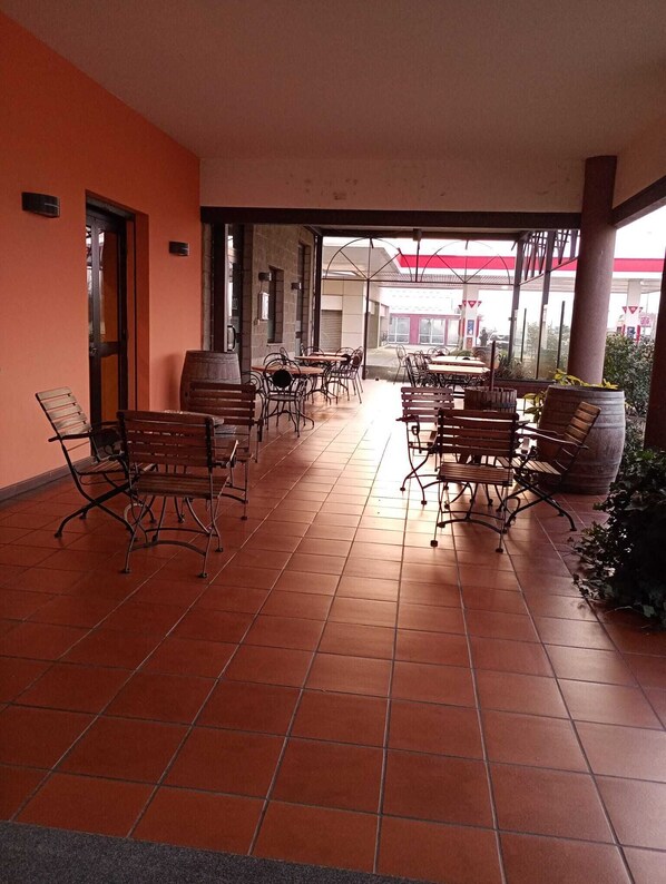 Une terrasse extérieure avec un sol carrelé, des chaises et des tables en métal.