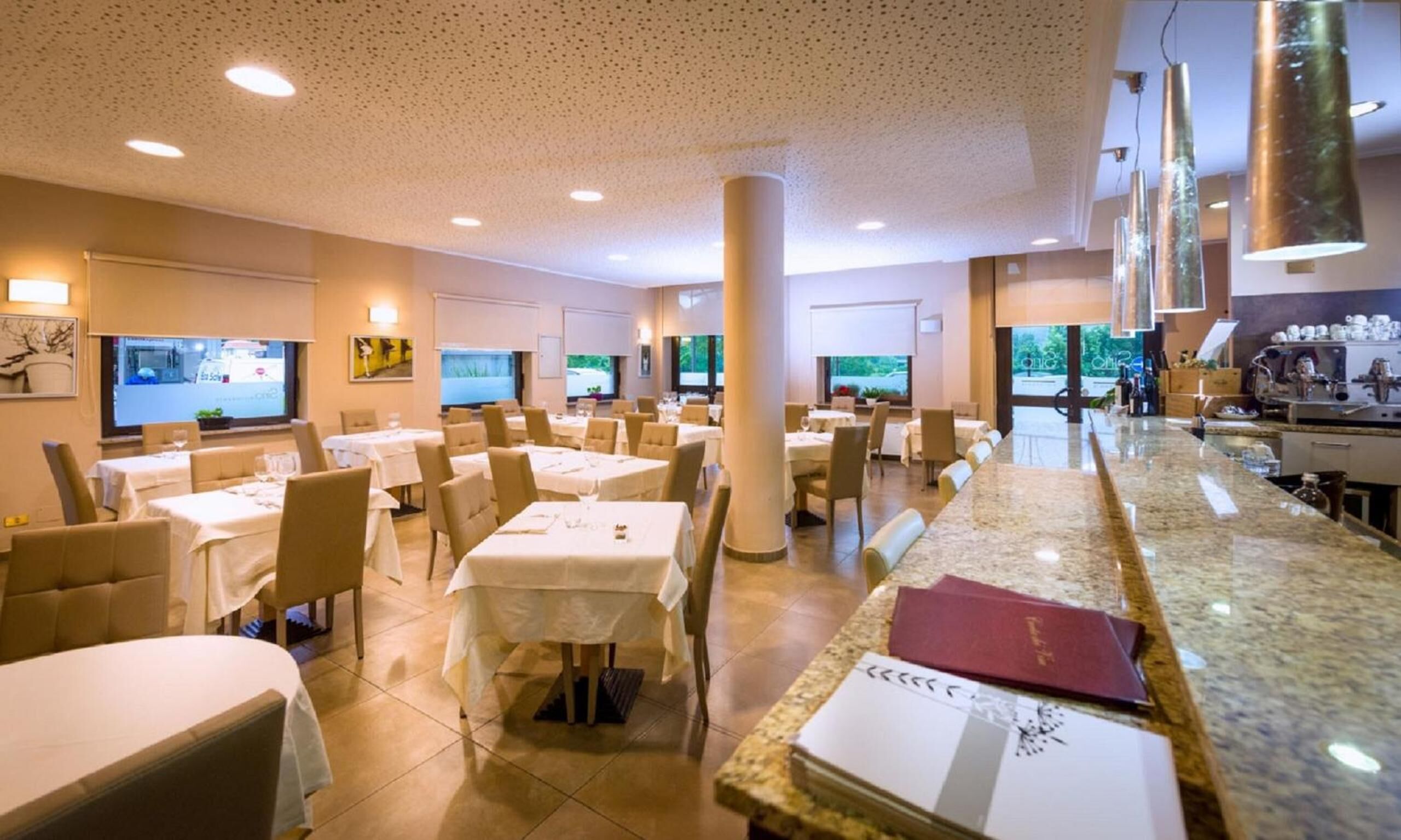 Un comedor de hotel con varias mesas, sillas y una barra.