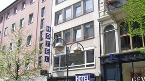 Un hôtel à plusieurs étages, dont la façade est ornée d’une grande enseigne indiquant « HÔTEL ».