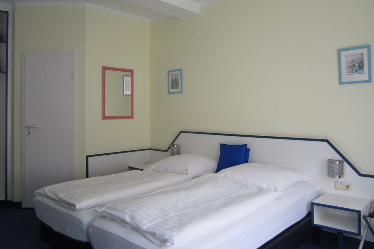 Ein Hotelzimmer mit einem Doppelbett, zwei Nachttischen und einer Tür.