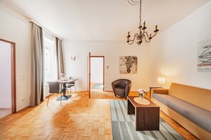 Una sala de estar moderna con un sofá, una mesa de centro, una zona de comedor con una mesa y sillas, una araña y obras de arte en las paredes.