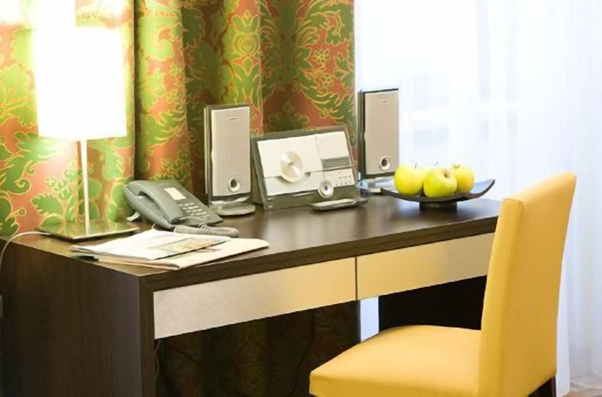 A hotel desk with a telephone, a computer, and a plate of apples.