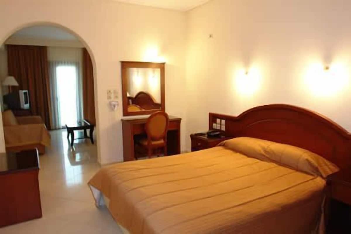 A hotel room with a bed, a desk with a chair, a television, and a mirror.