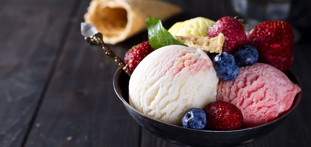 A bowl of ice cream with strawberries and blueberries.