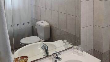 A bathroom with two sinks, a toilet, and a shower.