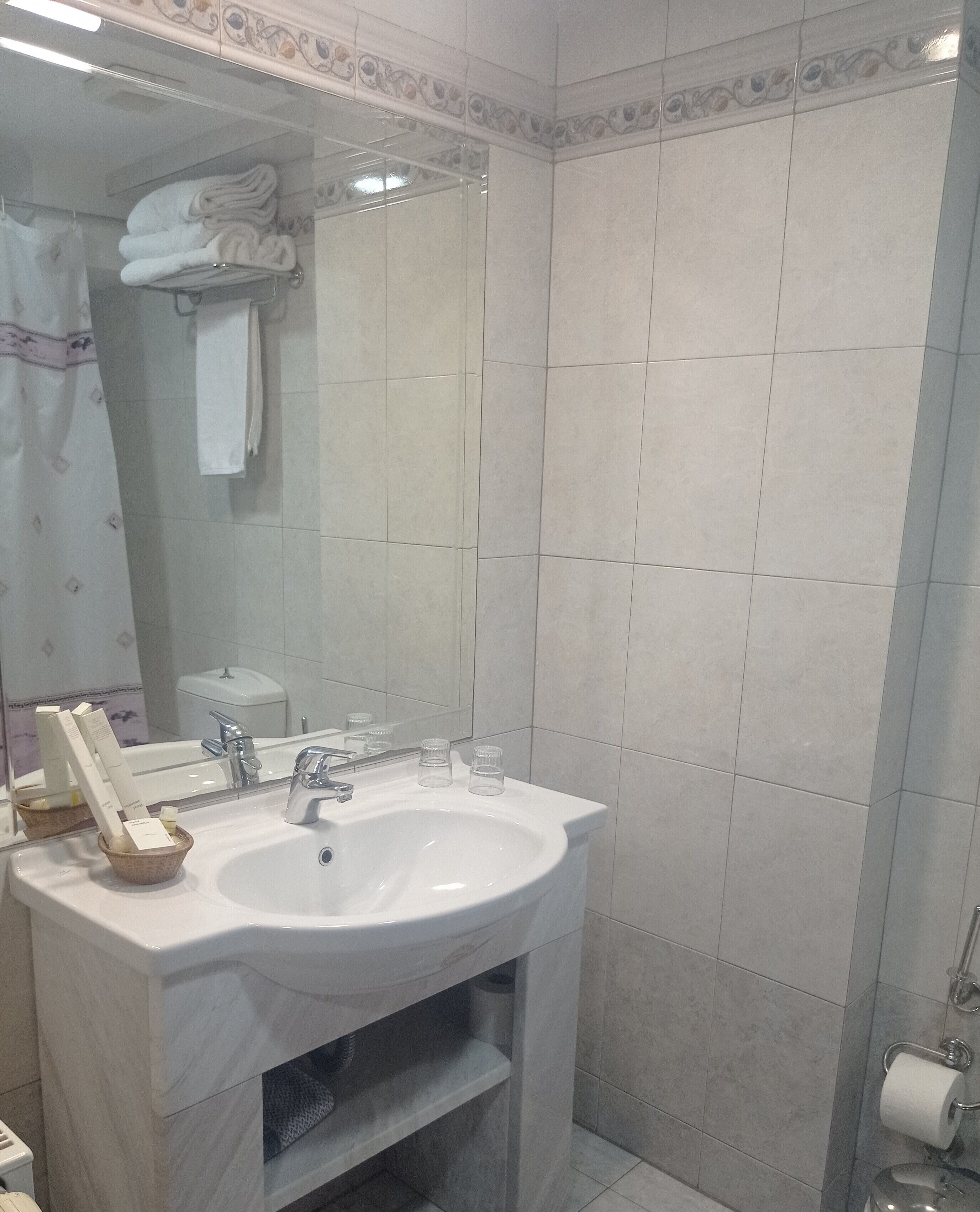 Ein Badezimmer mit Waschbecken, Spiegel und gefliesten Wänden.