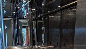 A modern elevator interior with metallic walls and a tiled floor. - Europa Beach Hotel (Delphi)