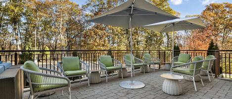 An outdoor patio with wicker furniture, a round table, and a large umbrella.