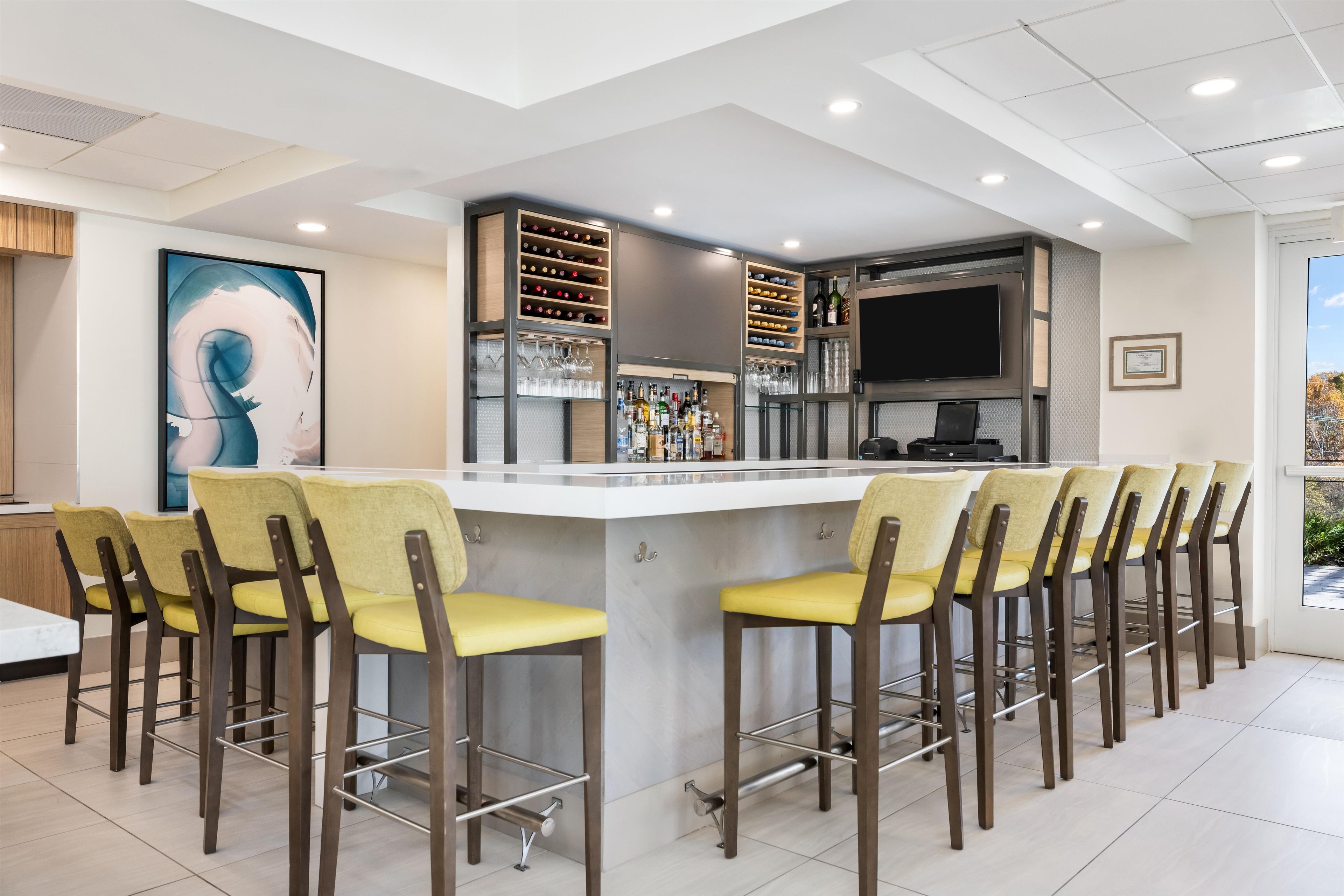 A modern bar area with a counter, bar stools, and a wine rack.