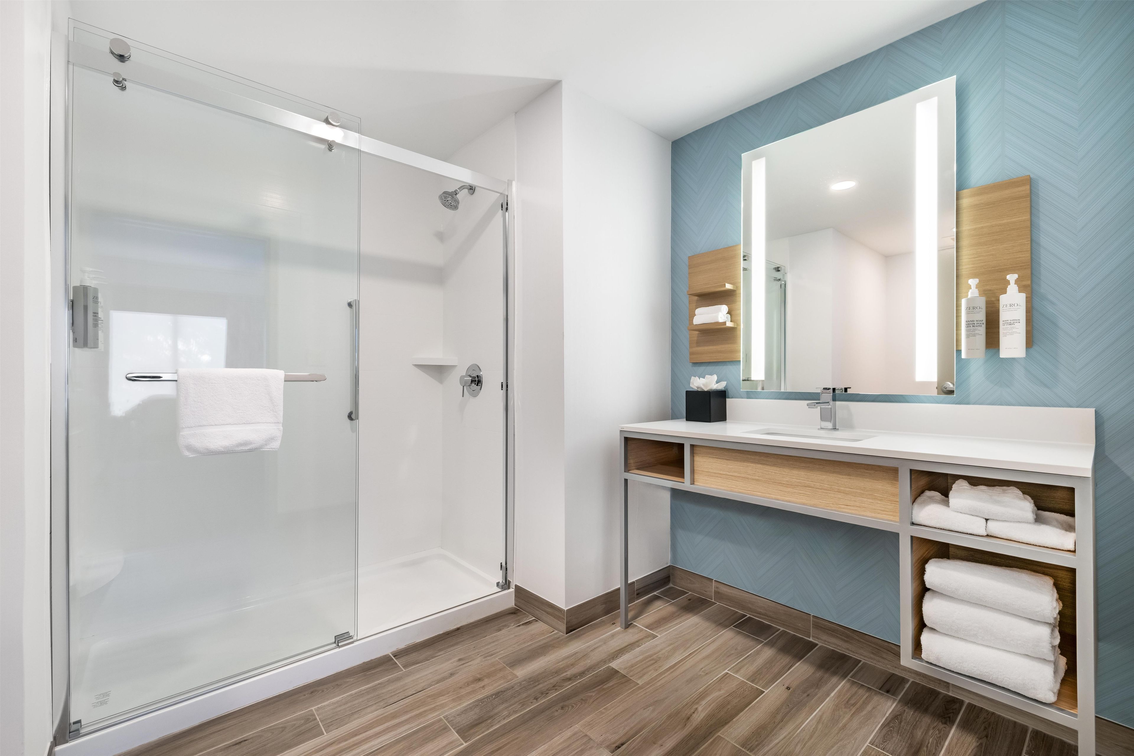 Ein modernes Badezimmer mit Duschkabine aus Glas, einem Holzbadezimmermöbel mit Spiegel und einer Wand mit Zickzackmuster.