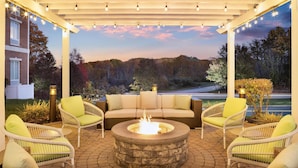 An outdoor patio with wicker furniture, a fire pit, and string lights.