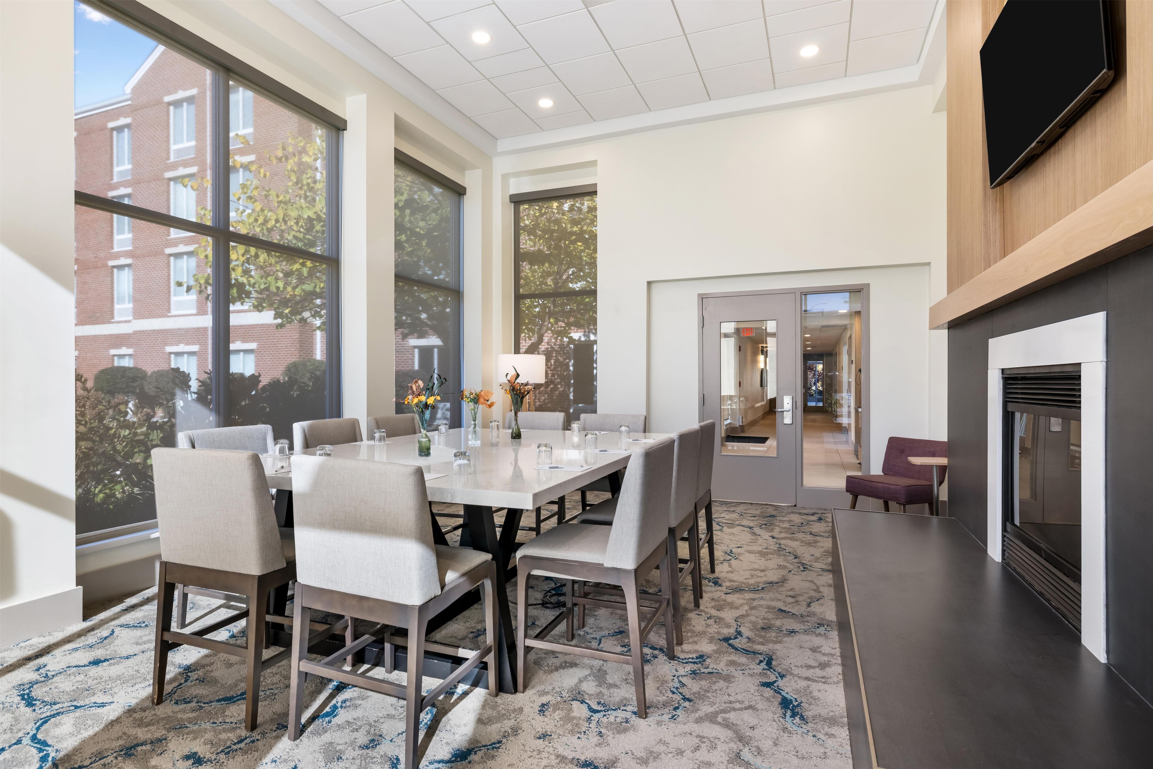 A modern dining area with a large table, chairs, and a fireplace.