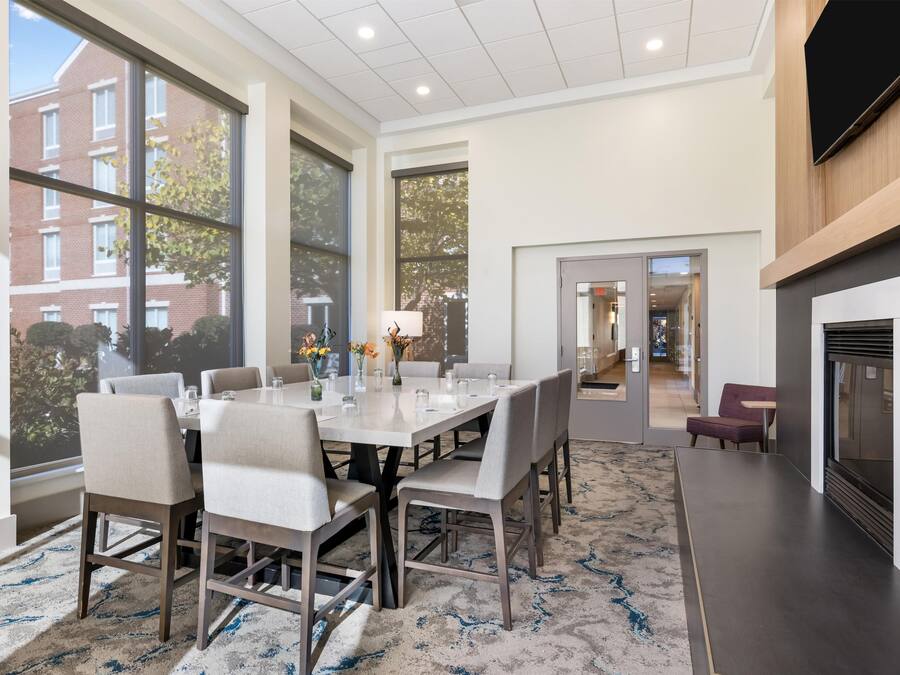A modern dining area with a large table, chairs, and a fireplace.